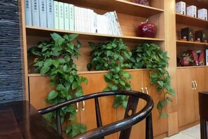 A wooden bookshelf with books and decorative plants. - Tonghuali Hotel (Lankao)