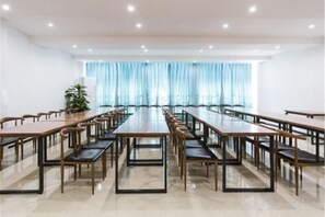 A conference room with long tables and chairs, large windows with curtains, and a potted plant. - Tonghuali Hotel (Lankao)