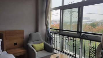 A hotel room with a balcony, a bed, a chair, and a small table.