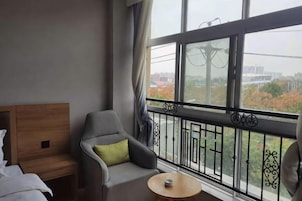 Habitación de hotel con balcón, una cama, una silla y una pequeña mesa.