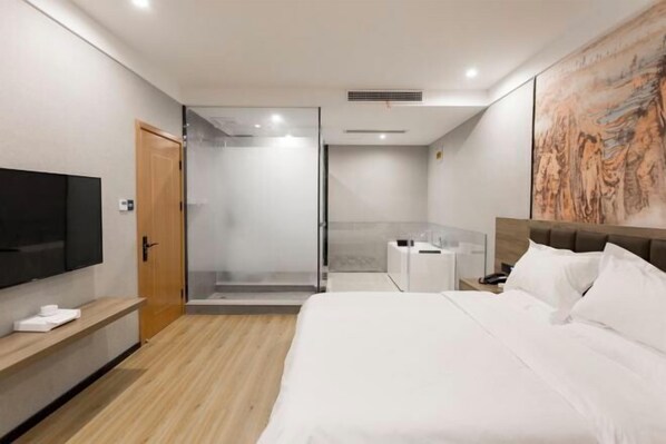 A modern hotel room with a large bed, a TV, a shower, and a painting on the wall. - Tonghuali Hotel (Lankao)