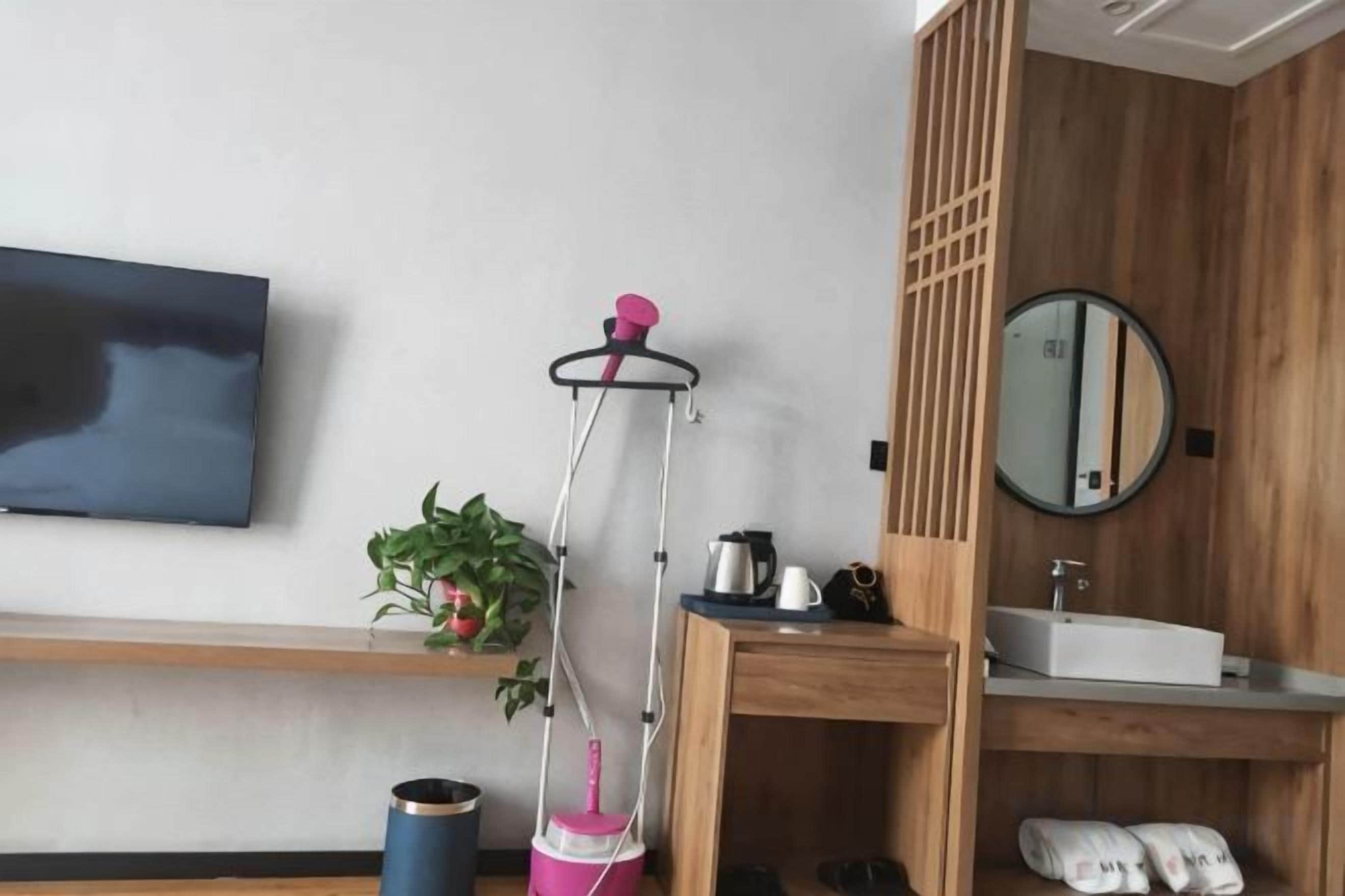 Un baño moderno con un mueble tocador de madera, un espejo redondo, un lavabo y un televisor montado en la pared.
