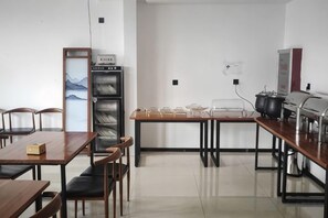 A kitchen with a dining table, chairs, a refrigerator, and a coffee machine. - Tonghuali Hotel (Lankao)