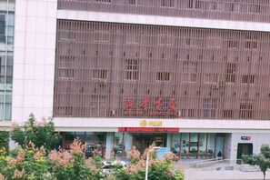 A building with a modern facade, large windows, and a prominent red sign. - Tonghuali Hotel (Lankao)