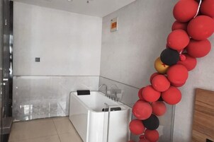 Un baño moderno con una bañera blanca, zona de ducha e inodoro de pared.