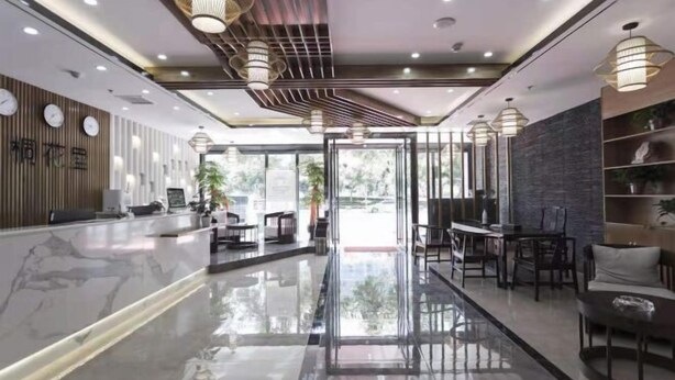 Un moderno hall de hotel con un mostrador de recepción de mármol pulido, zona de estar y grandes ventanales que ofrecen vistas al exterior.
