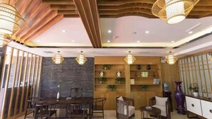 Un interior moderno con comedor, repisas de madera con plantas y una pared decorativa de piedra.