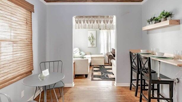 Una sala moderna con comedor, techo de madera y vista hacia un comedor con mesa dispuesta para dos.