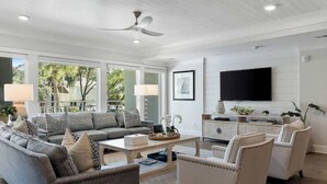 A modern living room with a sofa, armchairs, a coffee table, and a television.