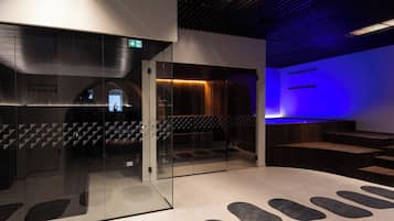 Een modern interieur met een glazen scheiding, een trap en een zithoek met een blauw verlichte wand.