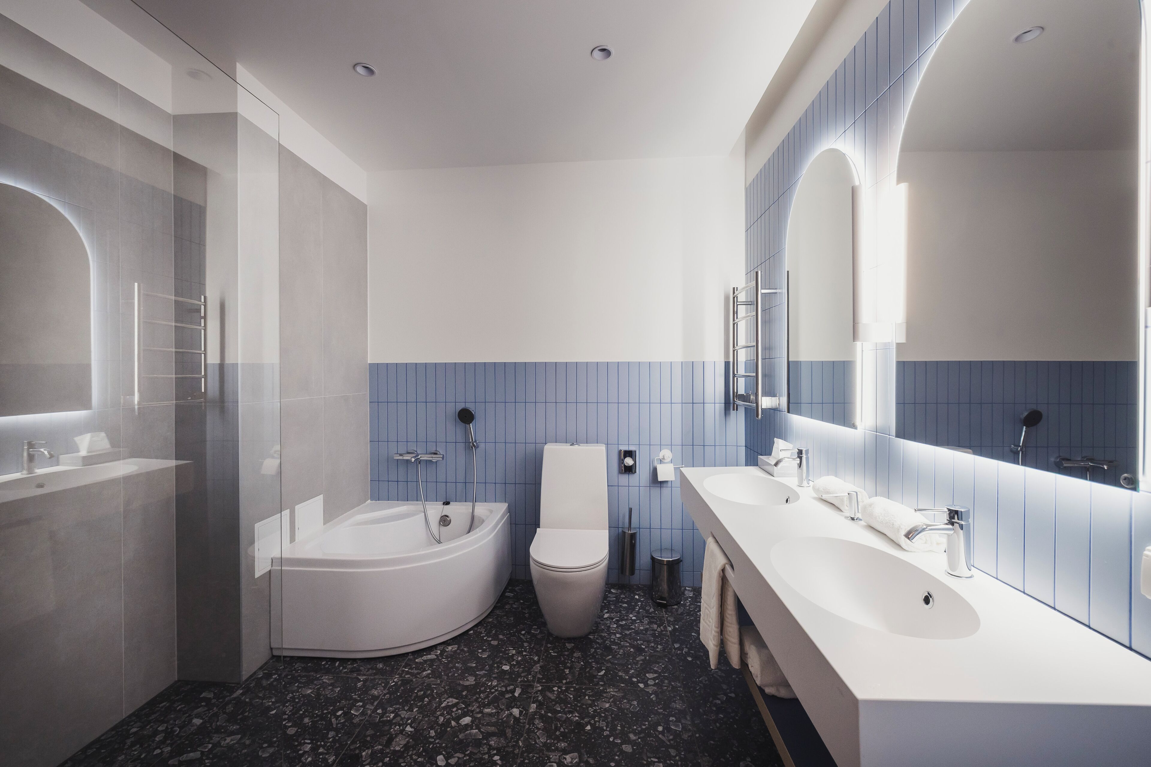 A modern bathroom with a bathtub, toilet, and two sinks.