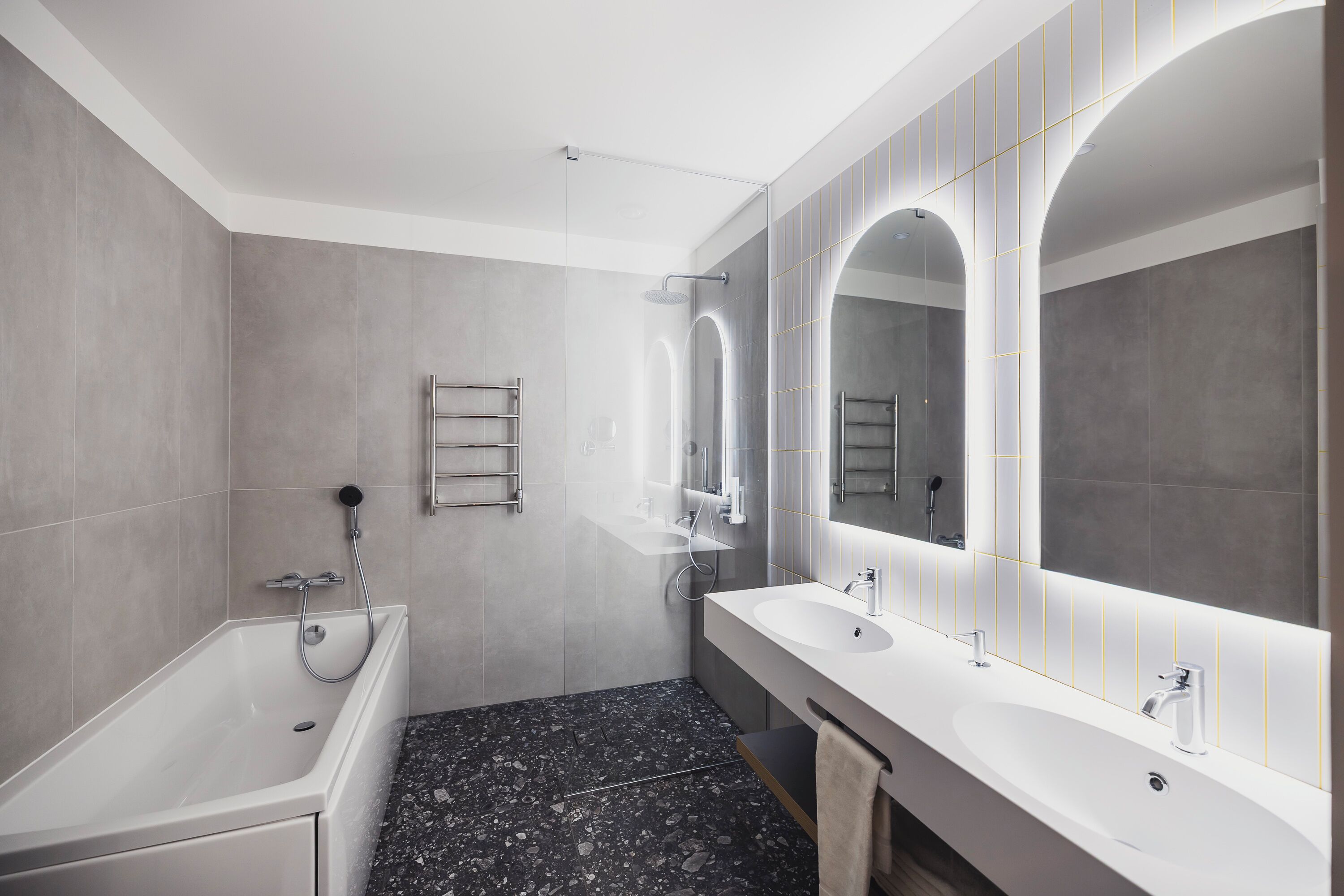 Un baño moderno con bañera, dos lavamanos y un espejo grande.