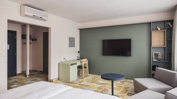 Habitació d'hotel amb un llit, escriptori, cadira, televisió i prestatgeria.