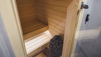Una sauna con listones de madera, un banco y un recipiente de piedra.