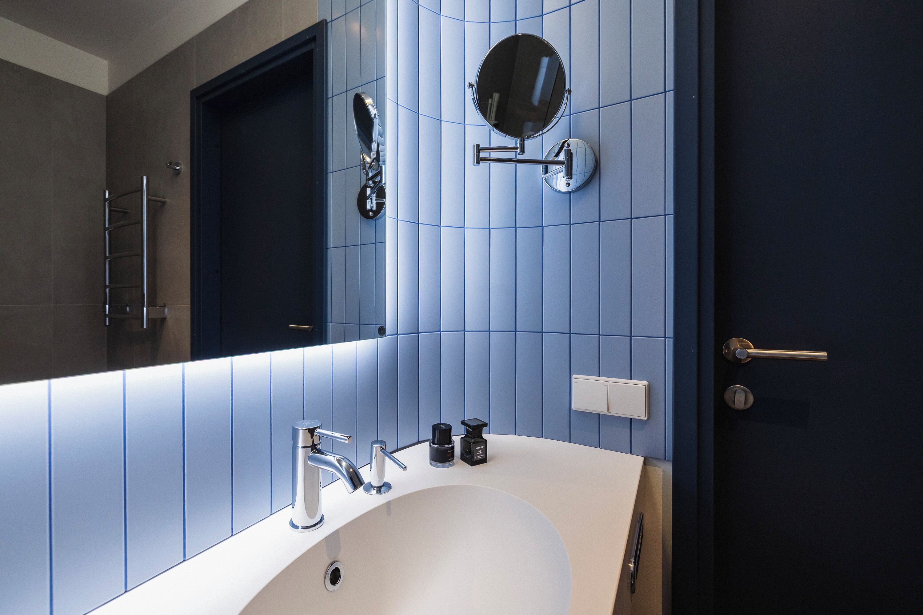 Un baño moderno con un espejo grande, un lavamanos blanco y una puerta.