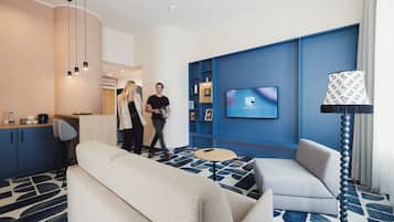 Un moderno vestíbulo de hotel con un sofá, un televisor montado en la pared y una zona de bar.