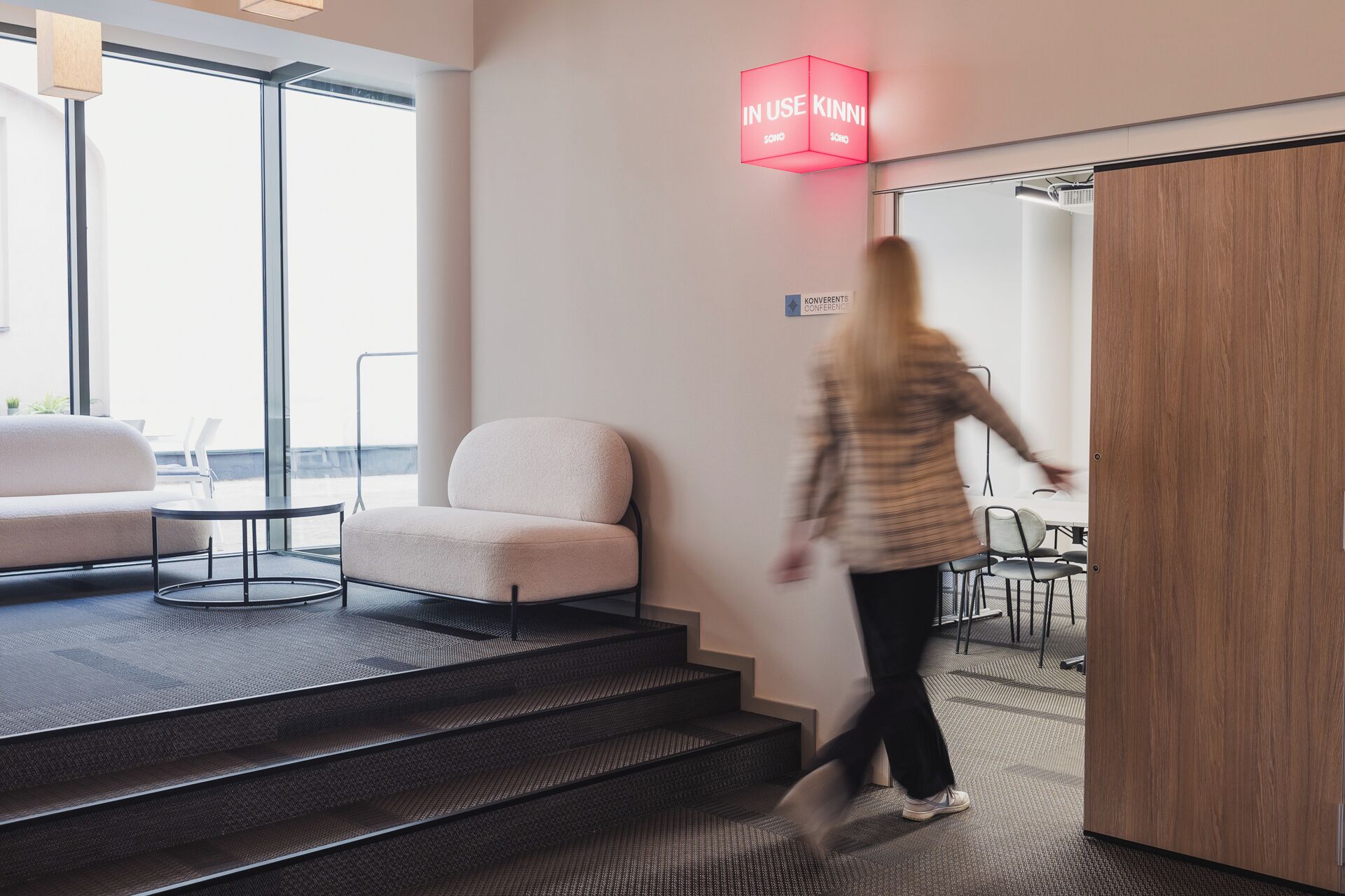 Un interior moderno con una escalera, una zona de estar y una sala de conferencias.