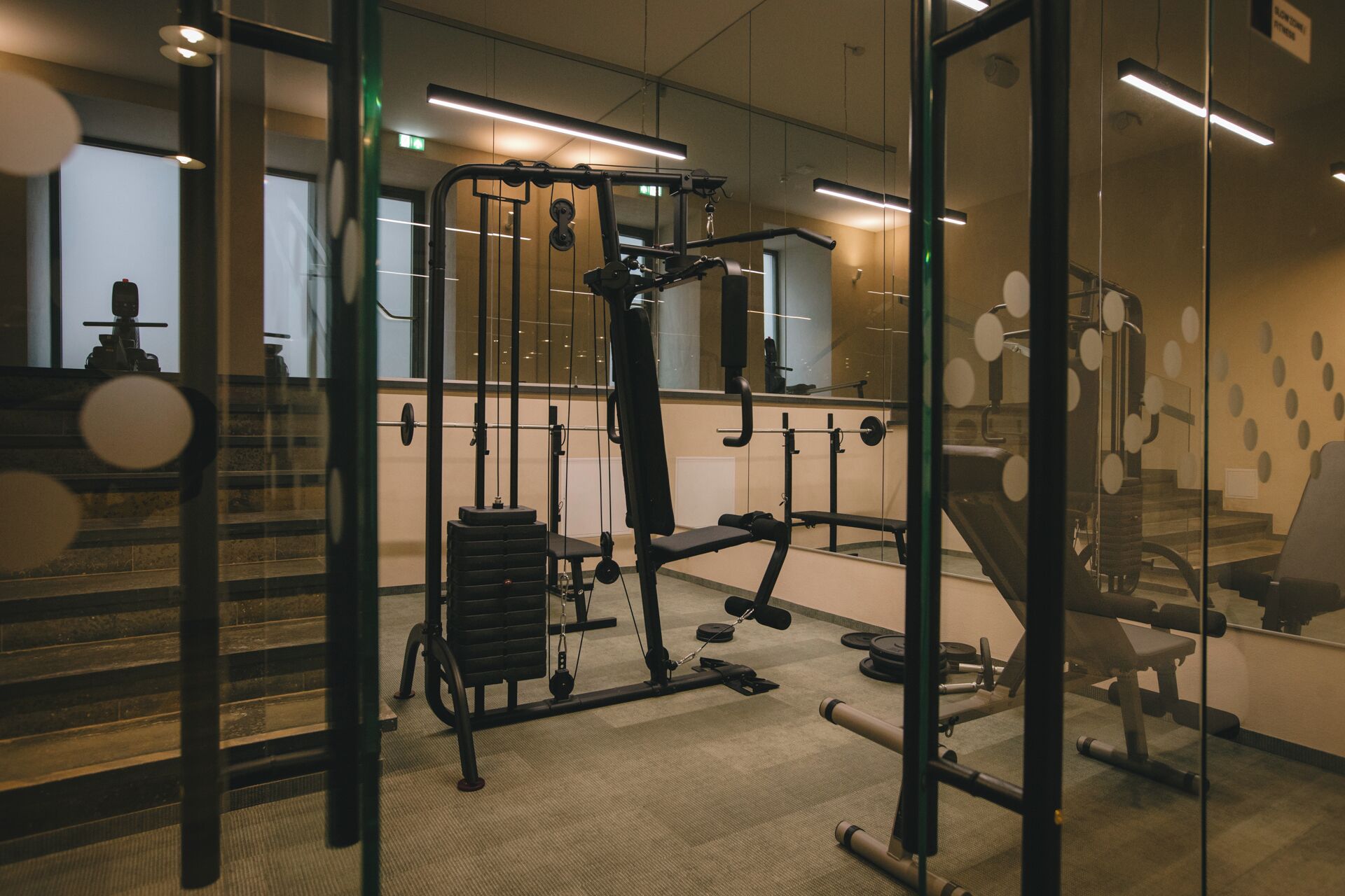 Un gimnasio con equipo de ejercicio, un espejo y una escalera.