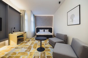 Een hotelkamer met een bed, een bureau, een stoel, een bank en een kleine tafel.