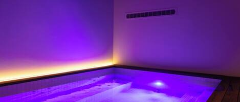 A spa area with a hot tub, wooden flooring, and a sloped ceiling.