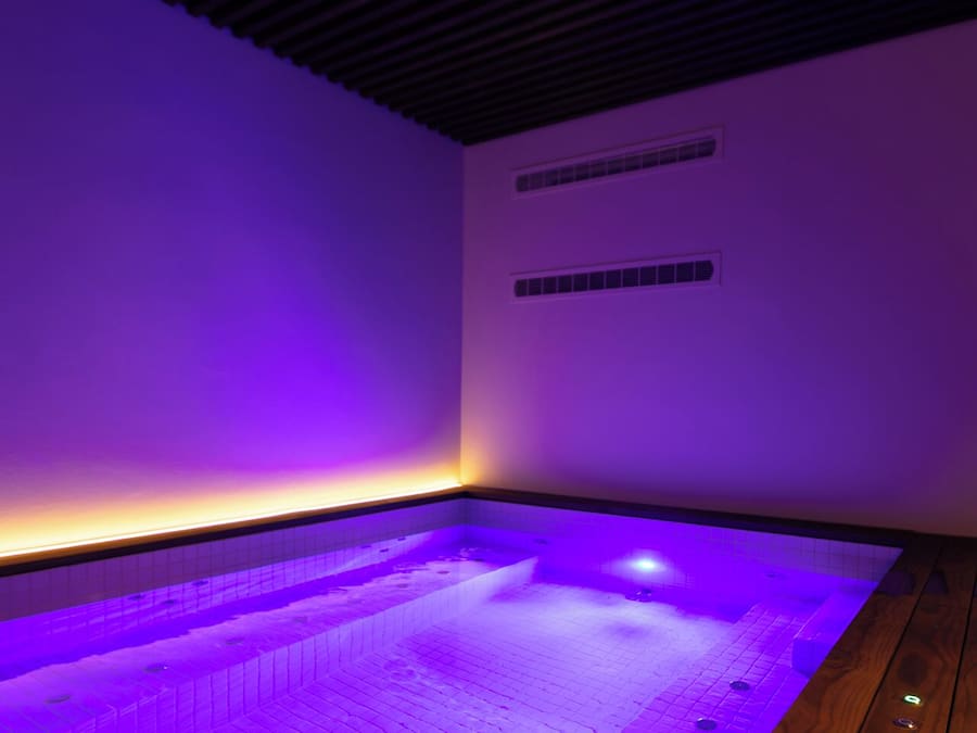 Un área de spa con hidromasaje, suelo de madera y techo inclinado.