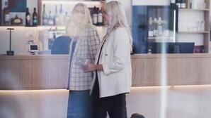 Aula, jossa on vastaanottotiski, oleskelualue ja baari, jonka hyllyillä on pulloja.