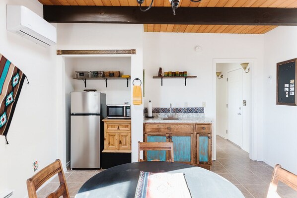 A compact kitchen with a refrigerator, microwave, and wooden cabinets.