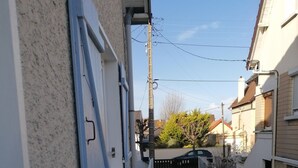 Une ruelle étroite, avec une porte en bois, une clôture en métal et un bâtiment à la façade blanche.