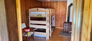 Ein Stockbett mit Stauraumschränken, ein Schreibtisch mit Spielzeug und ein Holzschrank.