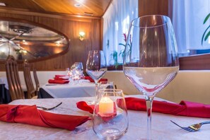 A dining table set with red napkins, a candle, and a wine glass. - Laerte Palace Hotel (Mogliano Veneto)