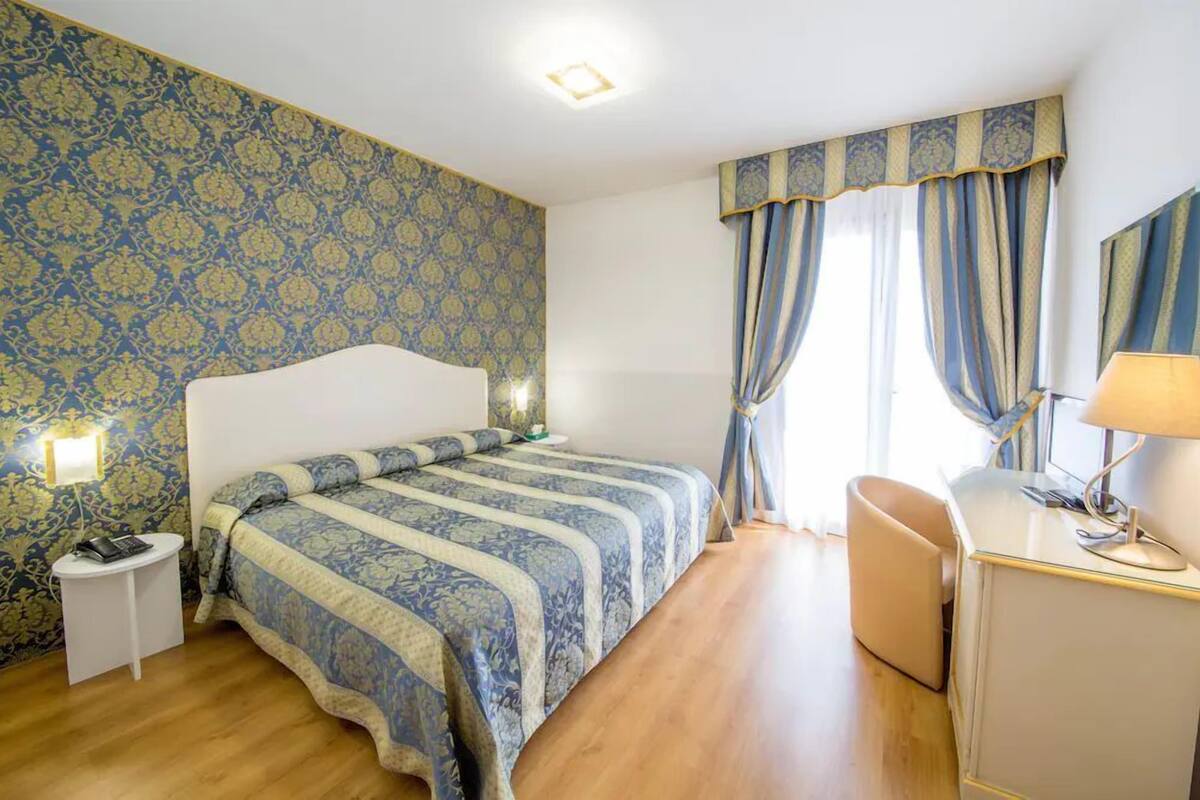 Une chambre à coucher comprenant un lit, une table de chevet, une lampe et un bureau avec une chaise.