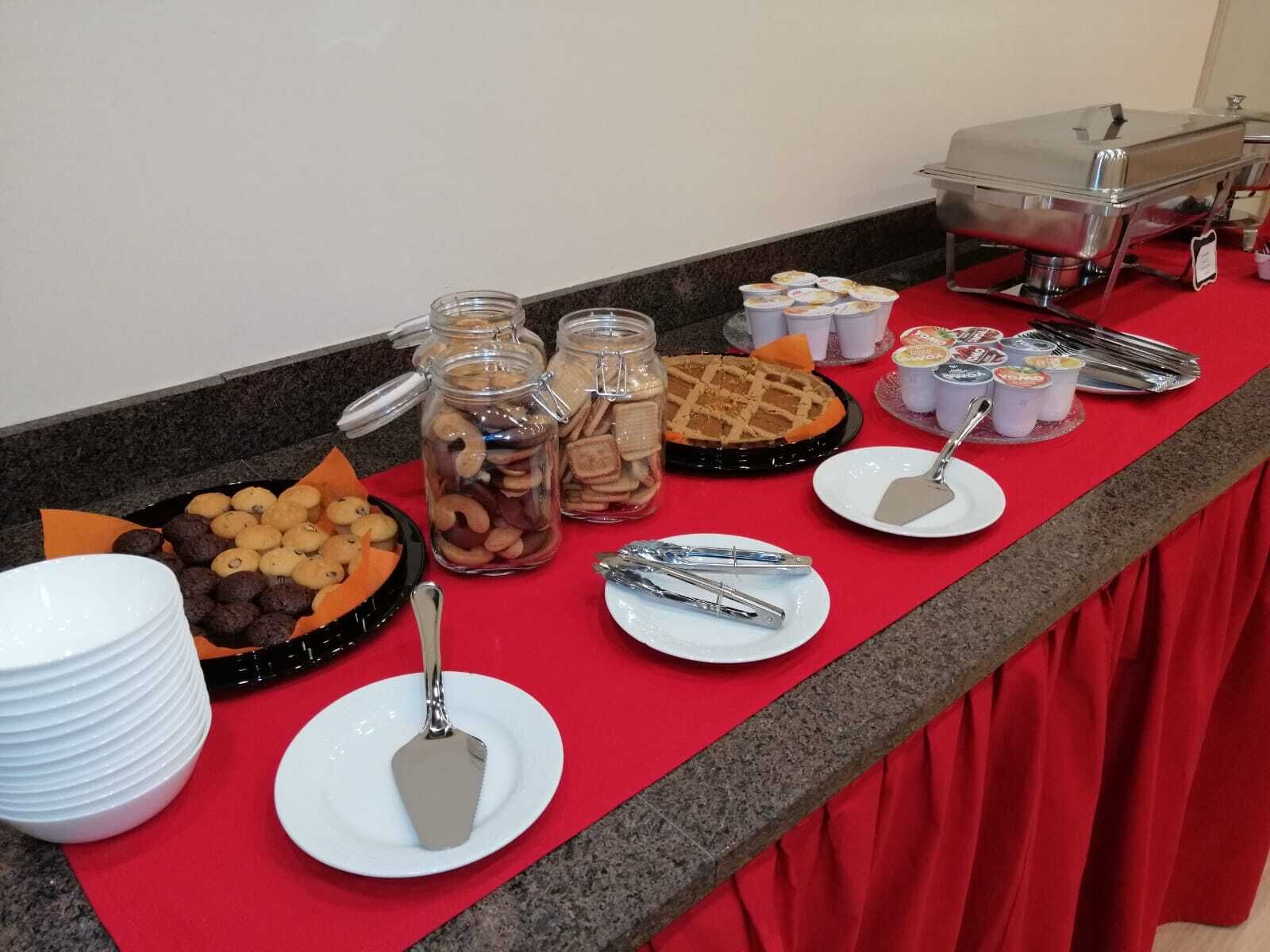 Een buffet met verschillende soorten eten, zoals koekjes, gebak en een taart, plus bestek en bakken.