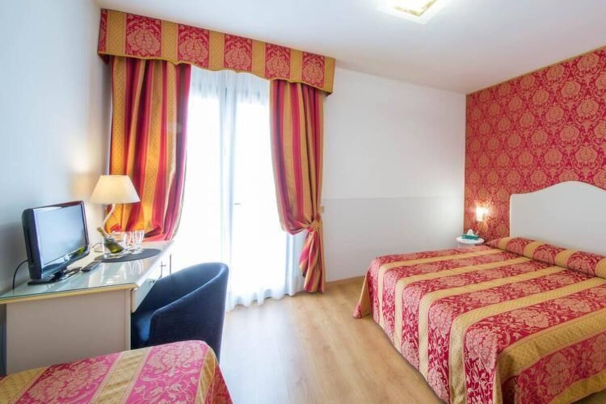 Une chambre d’hôtel avec deux lits, un bureau avec un ordinateur et une chaise.