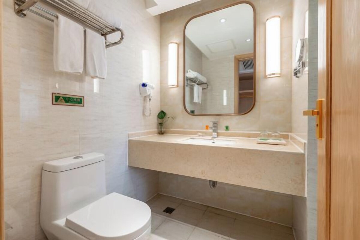 Een moderne badkamer met toilet, wastafel en spiegel.