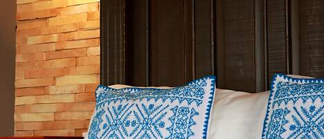 A bed with blue and white patterned bedding, a brick wall, and a wooden headboard.