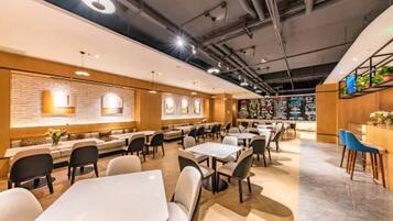 Un restaurante moderno con varias zonas de estar, incluyendo mesas y cabinas, además de un mostrador con una vitrina de menú.