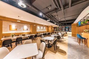 Un restaurant modern amb diverses zones d'ambientació, incloent taules i seients, i una barra amb un mostrador de menús.
