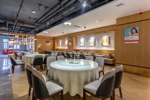 A modern dining area with round tables, chairs, and a central glass table.