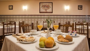 A dining table set with plates of food, glasses of orange juice, and a vase with flowers.