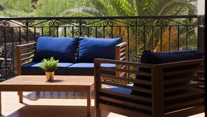 A balcony with a wooden bench, a small table, and a sofa with blue cushions.