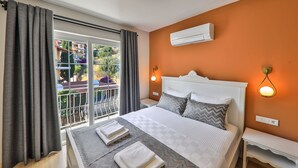 Ein Schlafzimmer mit Bett, Nachttisch, Klimaanlage und Blick auf einen Balkon.