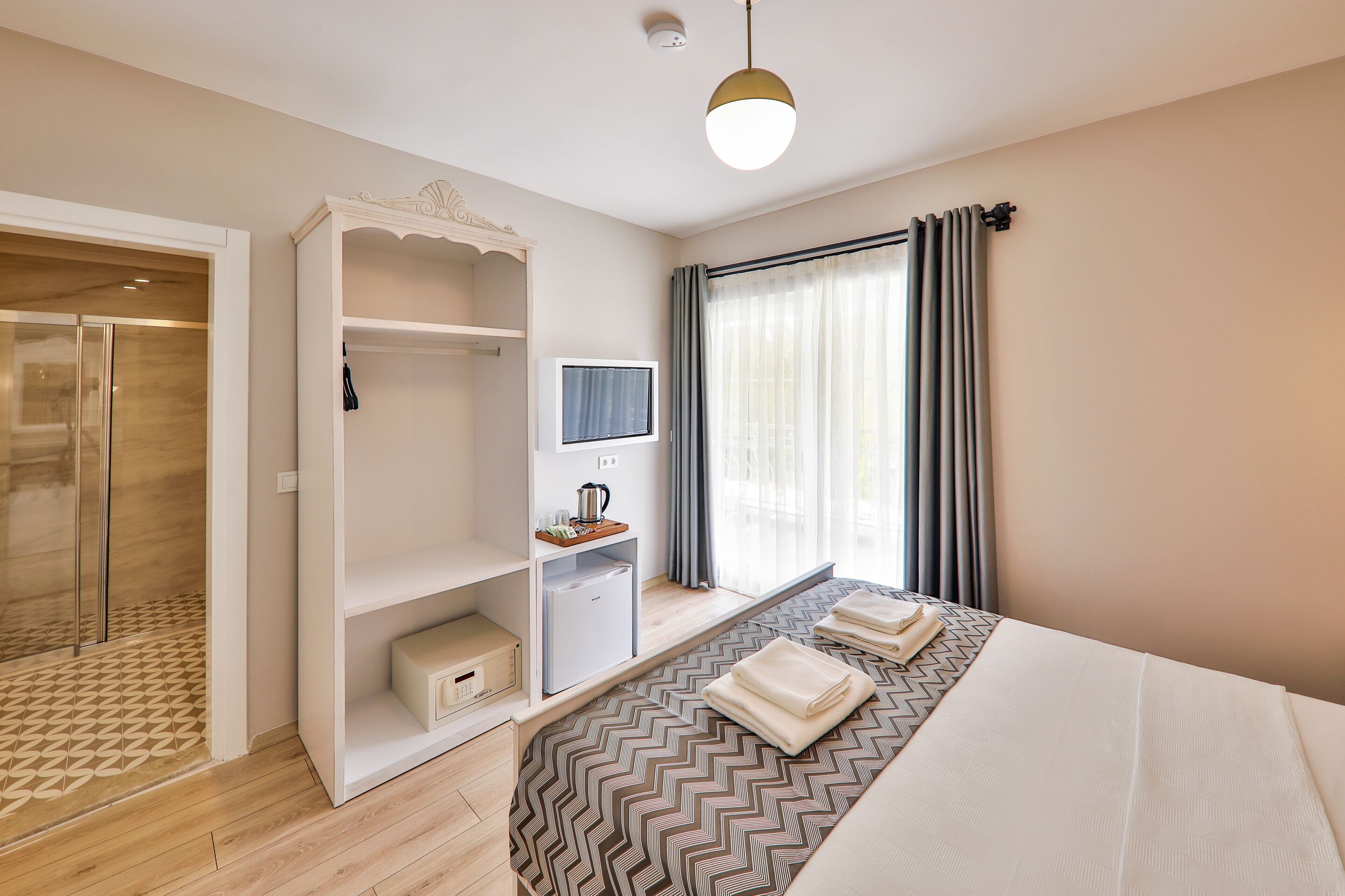 Een hotelkamer met een bed, een kledingkast, een televisie en een douche.