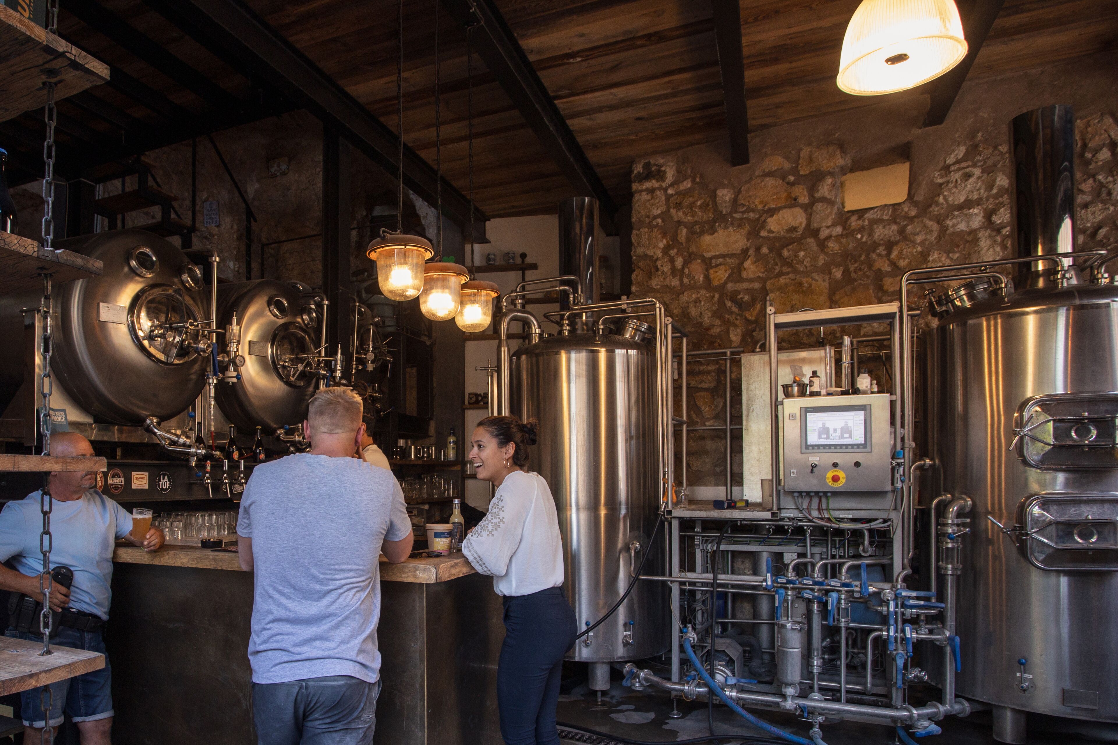 A brewery with stainless steel tanks, a bar area, and a control panel.