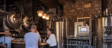 Una birreria con serbatoi in acciaio inossidabile, una zona bar e un pannello di controllo.