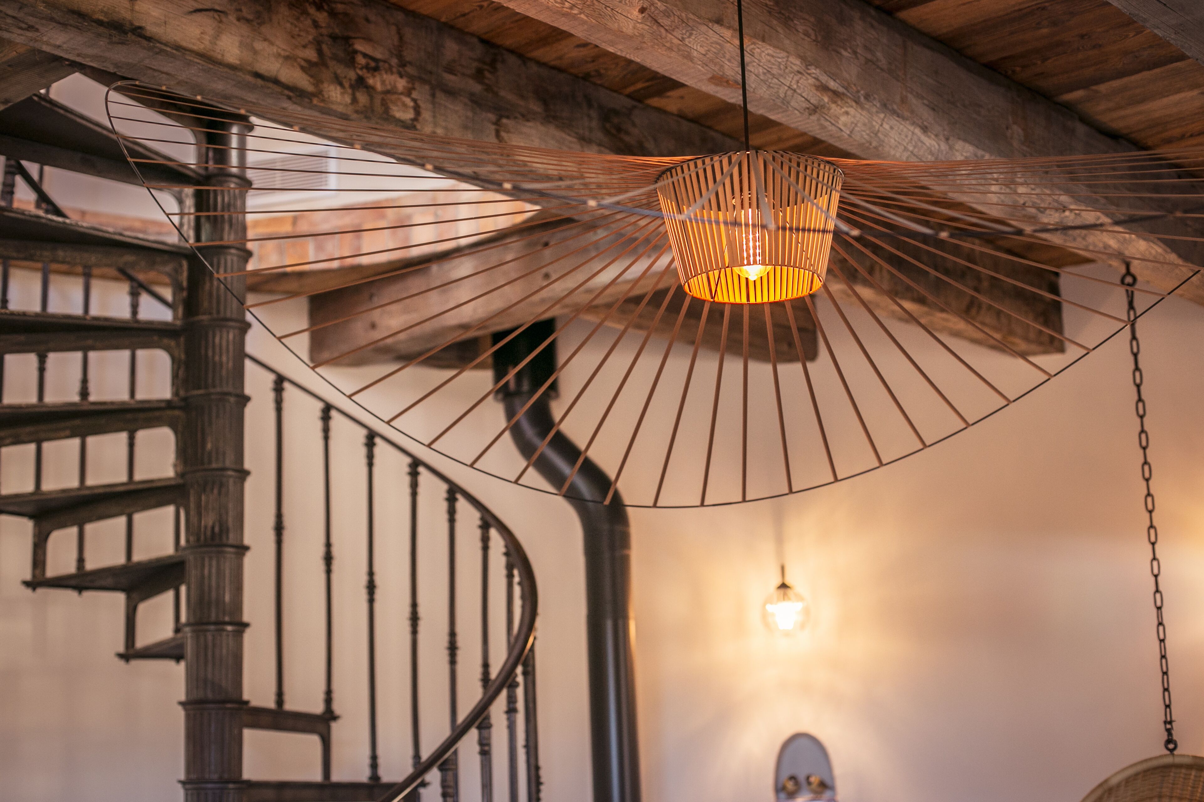 A spiral staircase with a hanging light fixture above it.