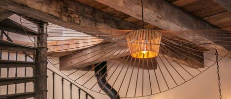 A spiral staircase with a hanging light fixture above it.