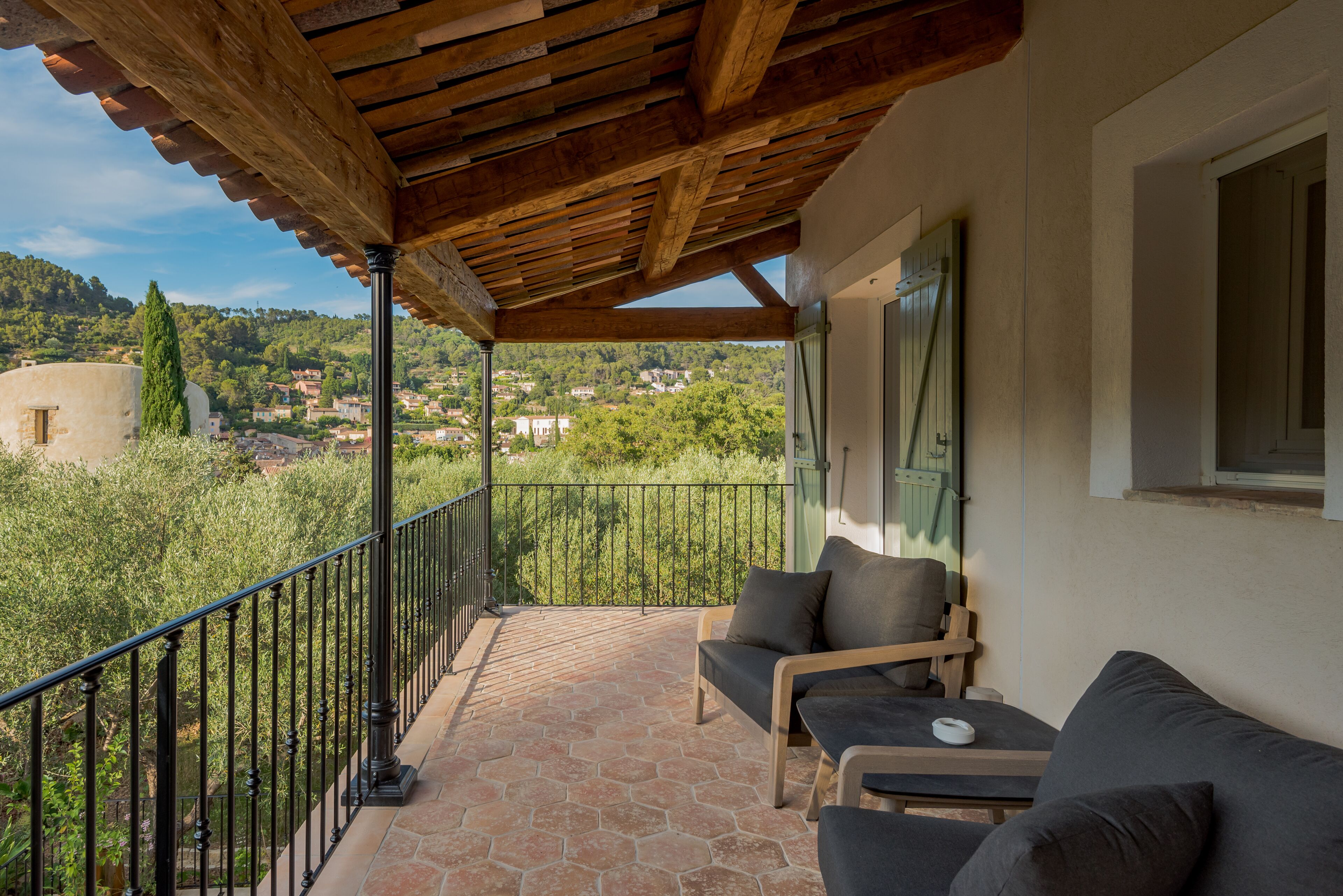 Un balcón con una pérgola de madera, un sofá y una mesa.