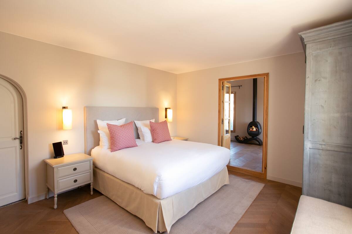 A bedroom with a large bed, bedside tables, a wardrobe, and a fireplace.