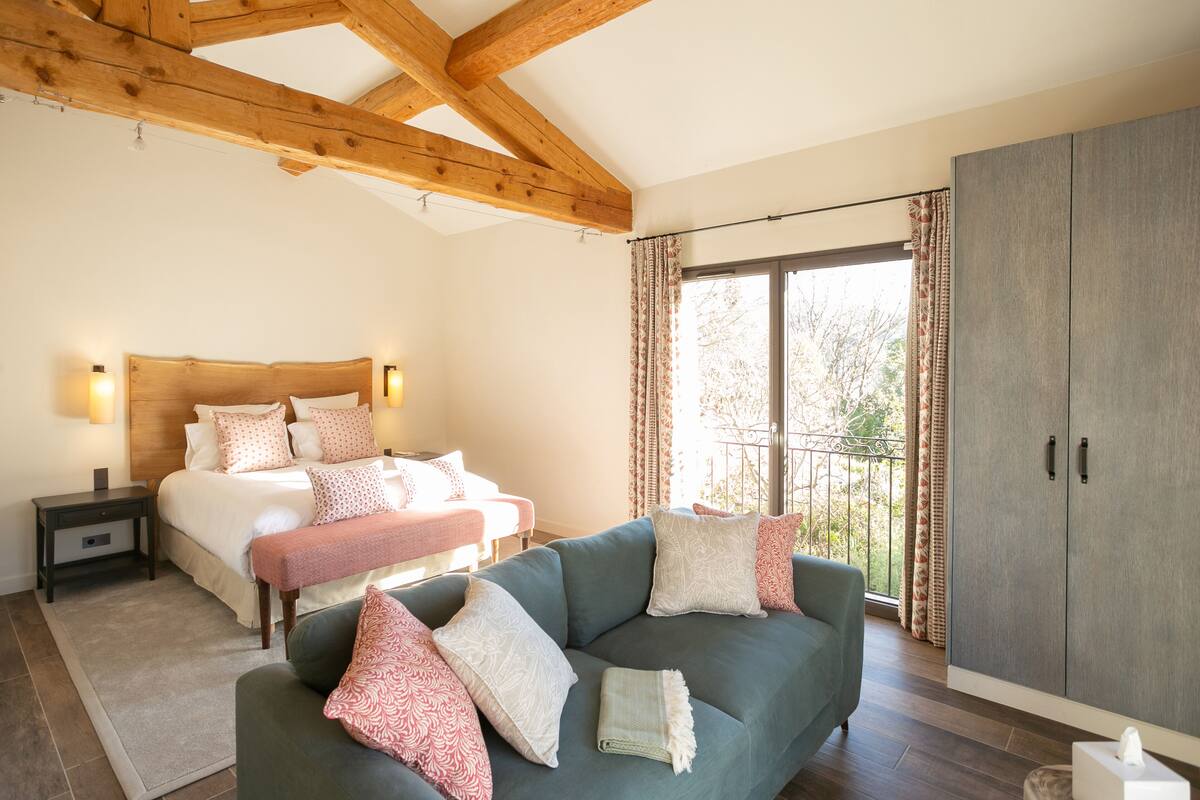A bedroom with a bed, bedside tables, a sofa, and a wardrobe.