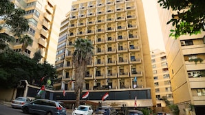 A multi-story hotel with balconies, a palm tree, and flags. - Legend Hotel (Beirut)